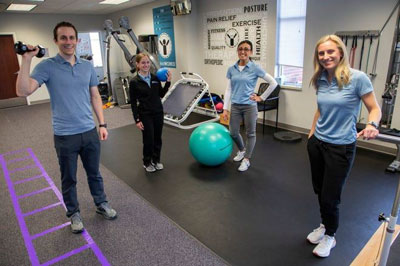 four young adults smiling and posing in a physical therapy environment