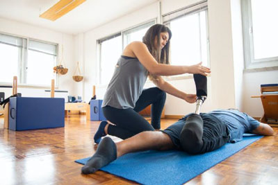 a physical therapist helping a patience with a prosthetic lower leg with a leg stretch