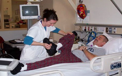 physical therapist holding and moving the leg of a patient in a hospital bed
