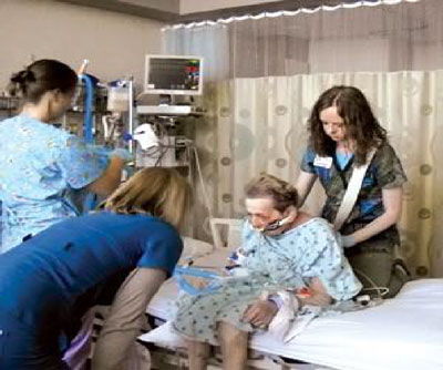 three hospital professionals assisting a patient sitting on a hospital bed