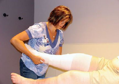 physical therapy professional assiting a patient who has a leg cast