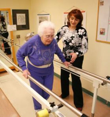 physical therapy professional assiting a patient with walking in a structure