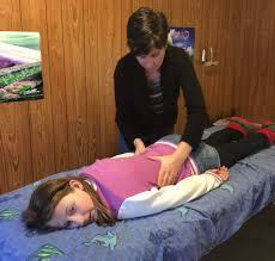 physical therapy professional examining a patient lying prone on a table.