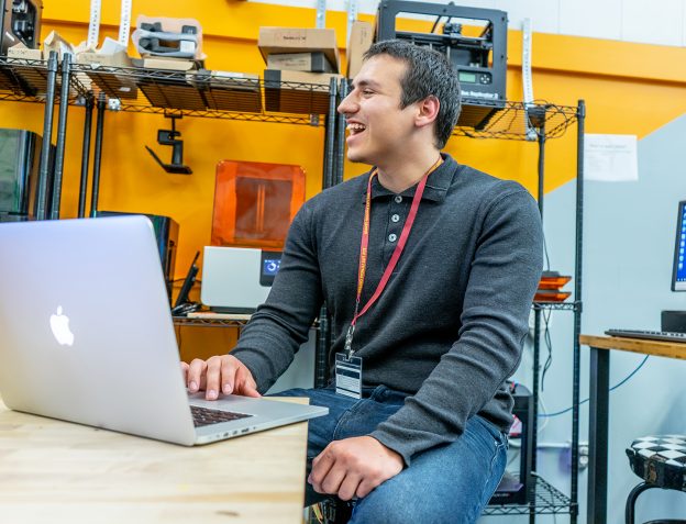 Carlo Lopez laughing and sitting at his laptop