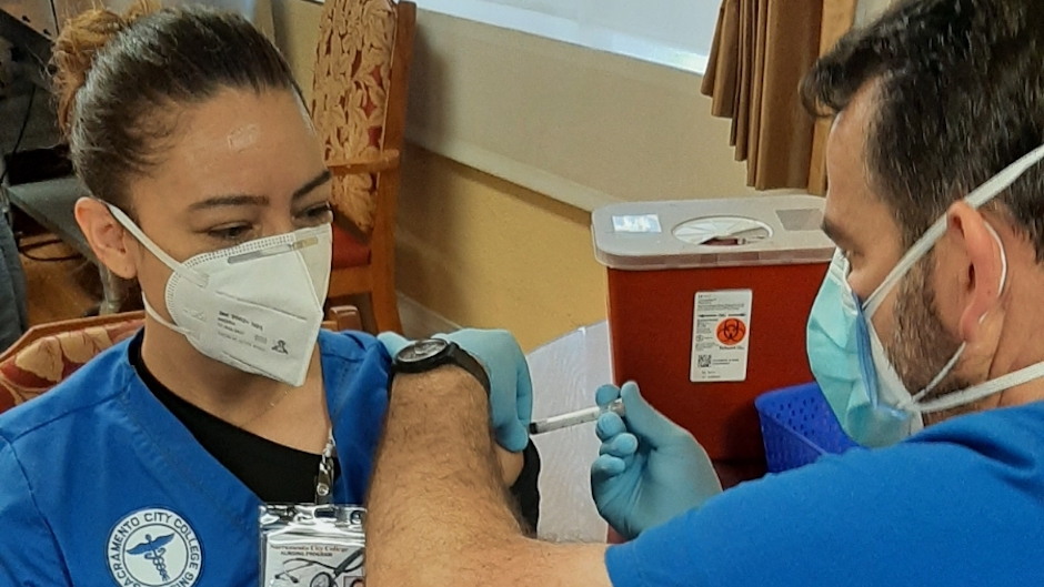 Sacramento City College student Annette receives a COVID vaccine from fellow student Jonathan. Annette and Jonathan helped administer vaccinations to community members under the supervision of SCC faculty at Pucci's Pharmacy.