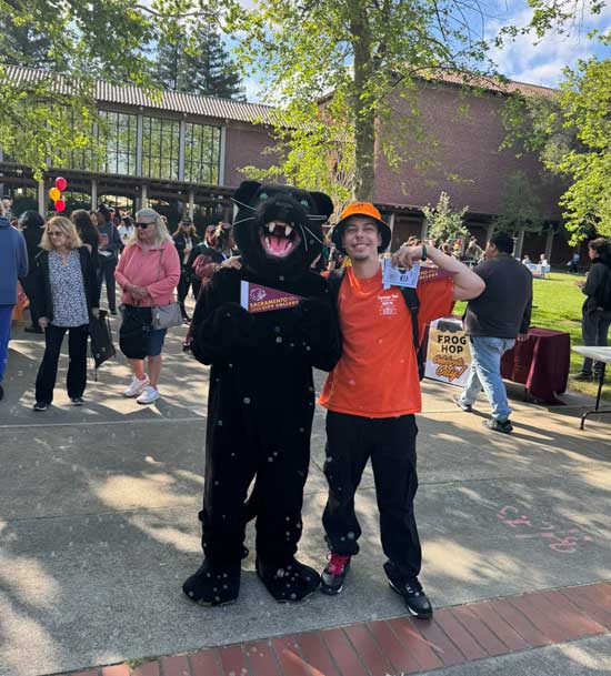 student posing with Panther mascot in the quad during a public event
