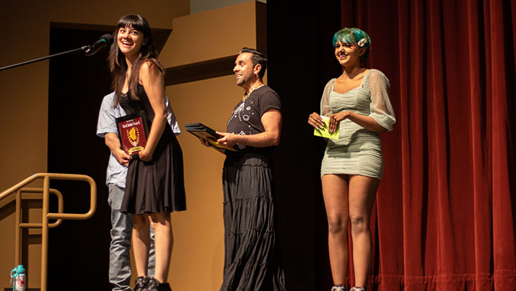 students standing on a stage with one receiving an awrd