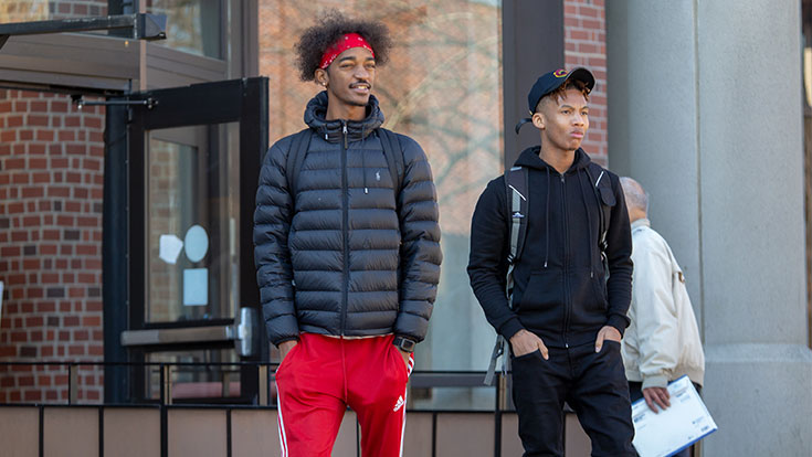 Two students standing in front of a brick building