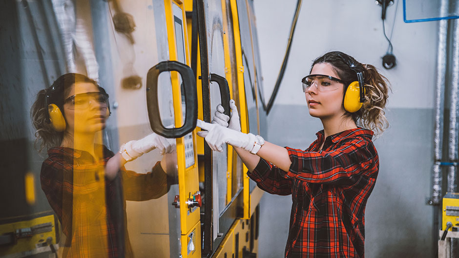 Female student working in a shop on the doors to a vehicle