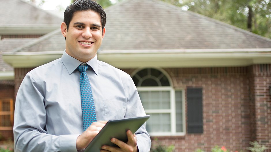 Realtor holding a clipboard and standing in front of a house