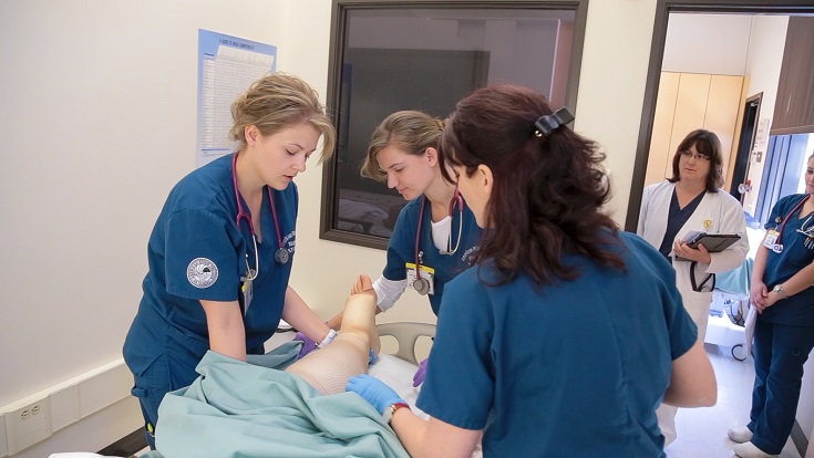 Nursing students working with a patient